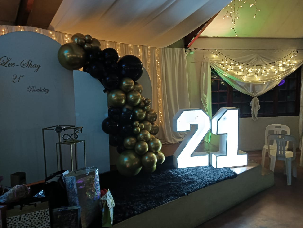 Black and gold birthday celebration setup with balloon arch and illuminated number display at Mayerskraal Wedding Venue