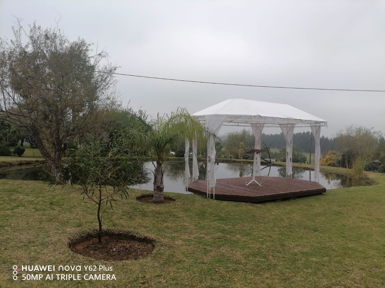 Outdoor wedding ceremony pavilion beside the pond at Mayerskraal Wedding Venue, surrounded by landscaped gardens and trees.