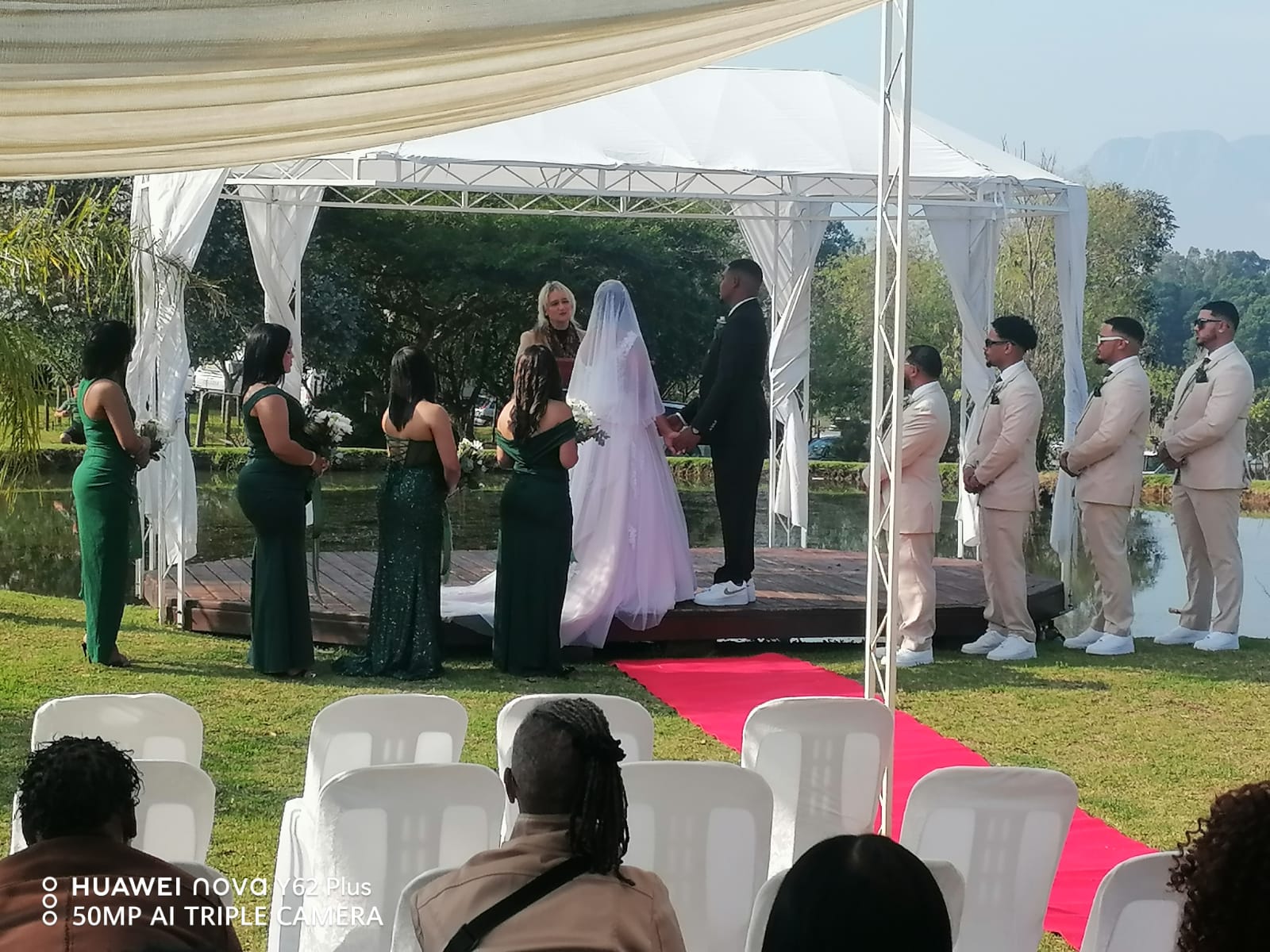 Bride and groom exchanging vows beneath a white ceremony pavilion overlooking the pond at Mayerskraal Wedding Venue.