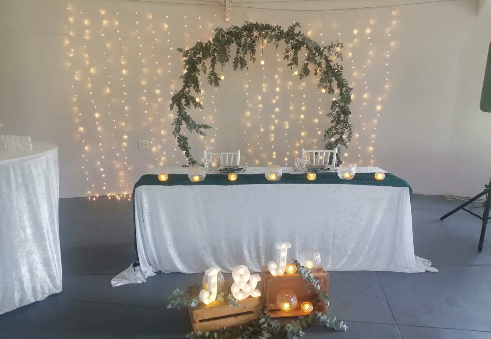 Romantic wedding table decorated with fairy lights, candles, greenery and a floral arch at Mayerskraal Wedding Venue.
